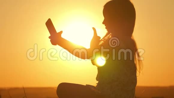 可爱的少女为自己拍照年轻漂亮的女孩在日落时在手机上自拍少女视频的预览图