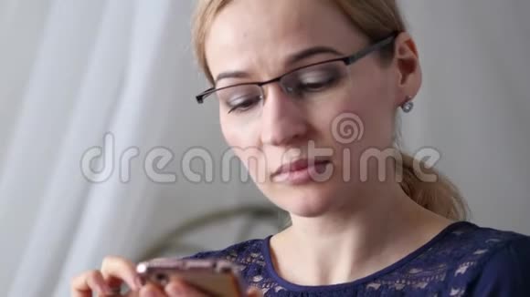 戴眼镜的金发女商人在智能手机上检查一些东西4K视频的预览图