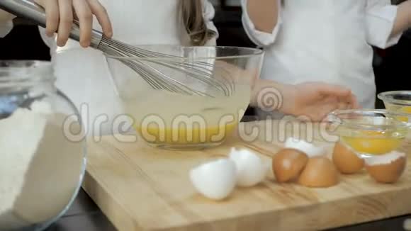 小女孩用玻璃碗在木桌上打鸡蛋视频的预览图