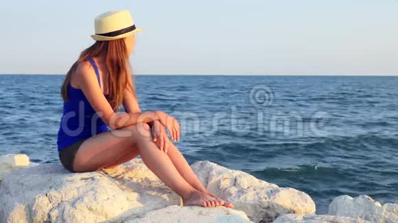 在巴拿马一个十几岁的女孩独自坐在海边的岩石上夏天的晚上视频的预览图