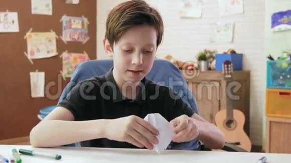 可爱的男孩折起折纸船玩它视频的预览图