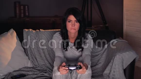 女人在游戏机上玩电子游戏就赢了坐在家里的沙发上视频的预览图