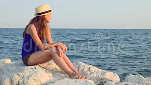 海滩度假妇女放松休息在石头海滩看海水视频的预览图