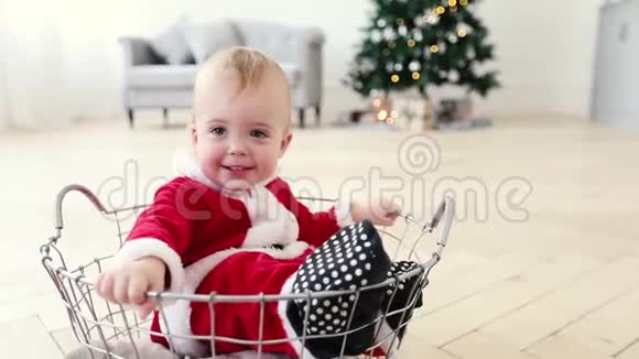 婴儿圣诞老人套装和圣诞树一起坐在篮子里视频的预览图