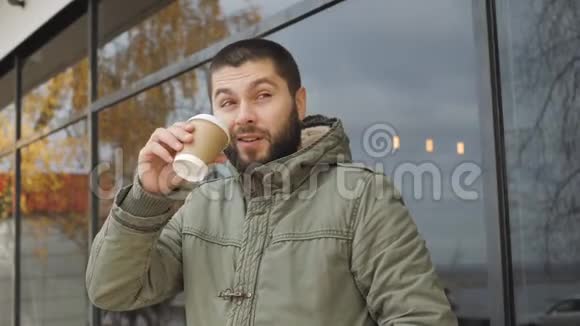 英俊的小胡子拿着一个杯子在户外的秋天喝热饮咖啡或茶视频的预览图