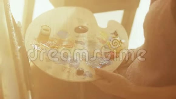 中年妇女艺术家正坐在日光浴室的画布上作画视频的预览图