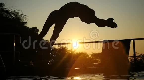 年轻人的剪影在夕阳下跳进游泳池的水中慢动作1920x1080视频的预览图