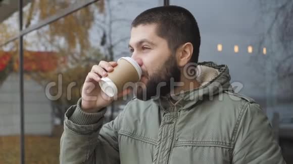 英俊的小胡子拿着一个杯子秋天在户外喝热饮咖啡或茶视频的预览图