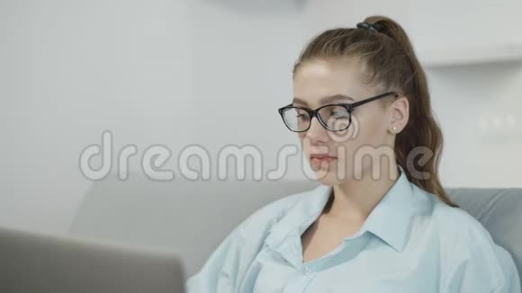 十几岁的女孩在家里用笔记本电脑在笔记本上打字准备考试或家庭作业视频的预览图