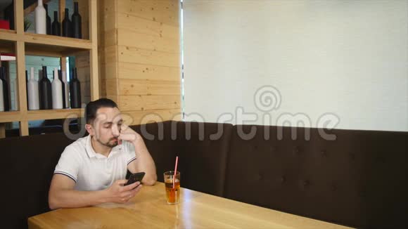 男人坐在咖啡馆里使用智能手机视频的预览图