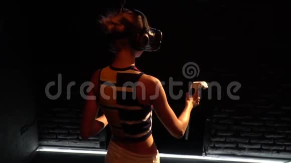 一个戴着虚拟现实眼镜的女孩手里拿着操纵杆在一个黑暗的房间里后视镜慢动作视频的预览图