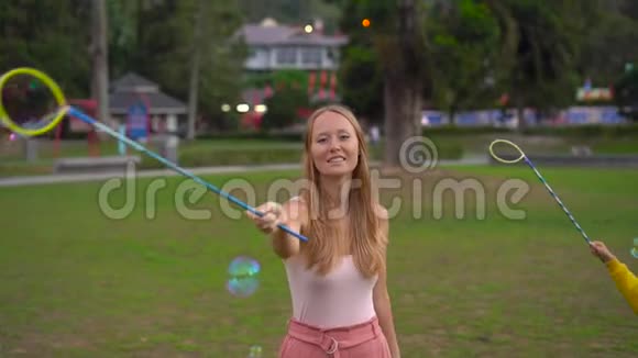 一个年轻女人在公园里做一个大肥皂泡的慢镜头视频的预览图