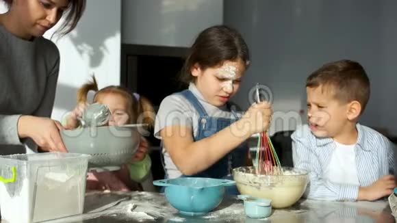 厨房里的孩子女孩搅动面团看着面团从花冠流出慢动作视频的预览图