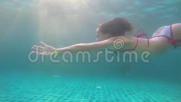 穿比基尼的年轻黑发女子正在水下缓慢地通过阳光游泳1920x1080视频的预览图