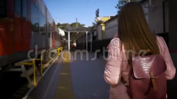 年轻漂亮的女人沿着火车沿着火车站走视频的预览图