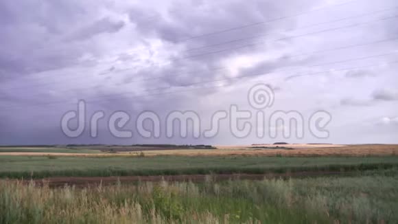 灰蒙蒙的天空下覆盖着干燥的绿草的巨大田野景观场景雨前农村的天空乌云密布视频的预览图