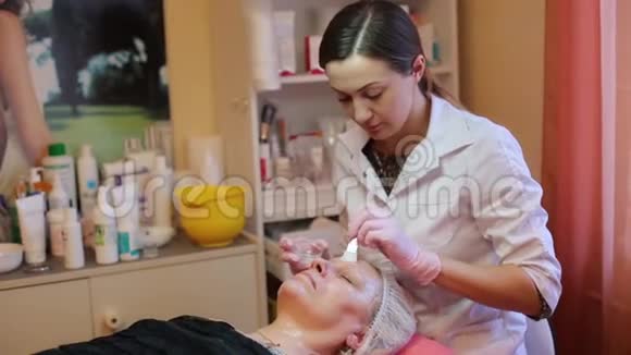 在美容院接受面部按摩的女人女人接受美容治疗特写美容师的双手工作视频的预览图