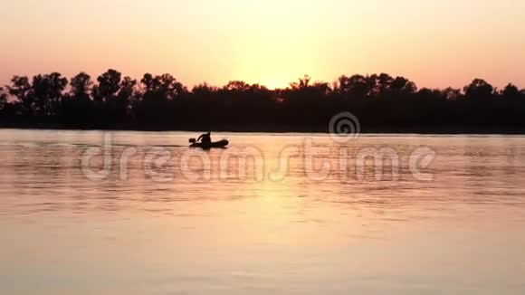 渔人剪影在背景夕阳下的河中钓鱼视频的预览图