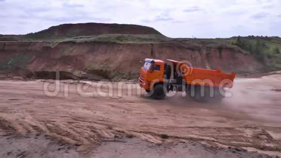 在沙土上驾驶自卸汽车的景观场景橙色自卸卡车在低地的采石场和地面视频的预览图
