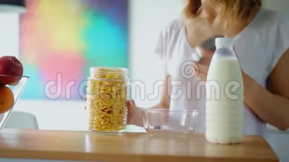 女人用厨房餐桌上的牛奶准备麦片视频的预览图
