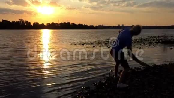 聪明人站在日落的河岸上他扔石头视频的预览图