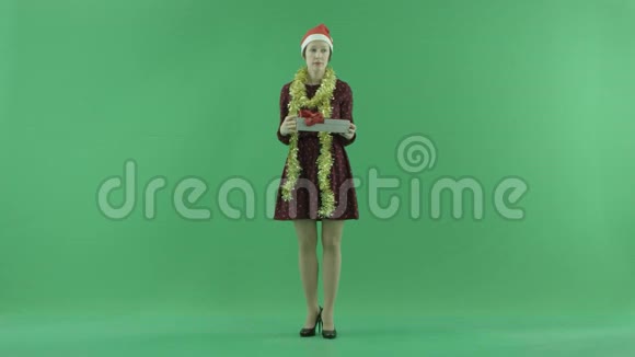 一位年轻女士正在绿色屏幕上打开一个空的圣诞礼物视频的预览图