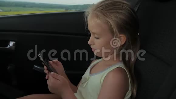年轻迷人的金发女孩坐在车里用智能手机视频的预览图