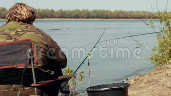 渔夫坐在河边的椅子上几乎是钓竿等待着咬人的背影视频的预览图