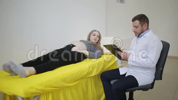 穿白色长袍的医生在病历中记录了孕妇的一般情况视频的预览图