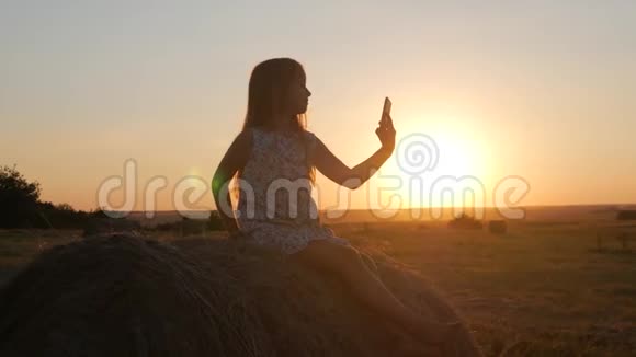 可爱的少女为自己拍照年轻漂亮的女孩在日落时在手机上自拍少女视频的预览图