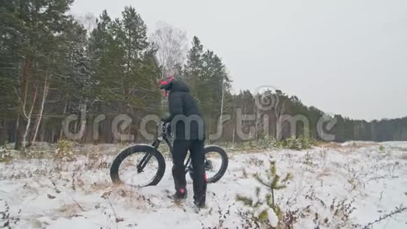 专业的极限运动员自行车在户外举起一辆胖自行车骑自行车的人留在冬天的雪林里与人同行视频的预览图