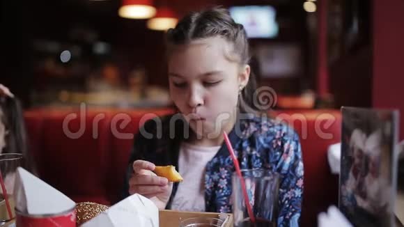 小女孩高兴地在咖啡馆里吃炸薯条快餐中的汉堡包和奶酪棒视频的预览图