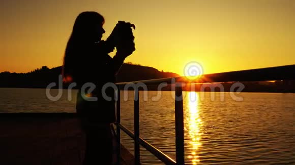 日落时分在码头上戴着虚拟现实眼镜的女人的剪影视频的预览图