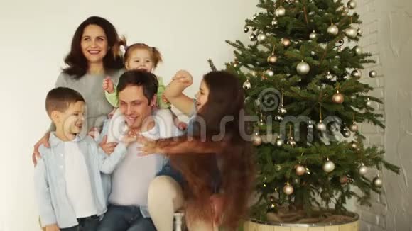 一个有三个孩子的大家庭在新年树附近拥抱圣诞快乐新年快乐视频的预览图