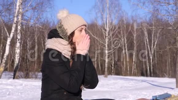 4K冬天穿帽子和黑色夹克的女人在森林附近打喷嚏视频的预览图