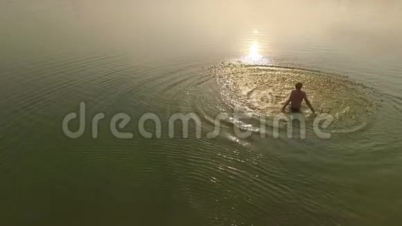 日落时分一个快乐的人用手在湖里泼水视频的预览图