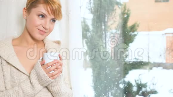 迷人的金发女郎靠近窗户边喝杯咖啡视频的预览图