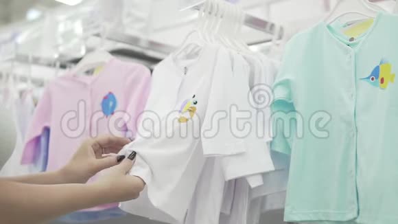 快乐的年轻女人为他们的孩子选择衣服商店里漂亮的女人在试衣服的质量视频的预览图