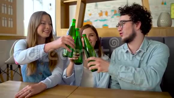 三个朋友坐在咖啡馆里喝水或啤酒交流愉快慢动作视频的预览图
