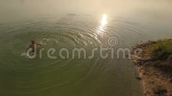 空中日落时一个年轻人在湖里转手视频的预览图