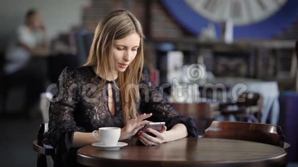 时尚的女人在一家小餐馆里喝咖啡坐在一张木桌旁上面有一个杯子视频的预览图