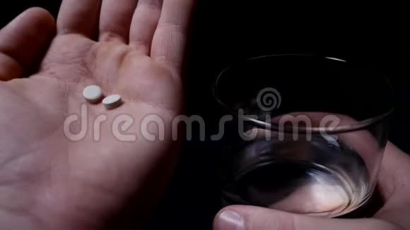 吃药手里拿着清水的药丸和杯子黑色背景视频的预览图