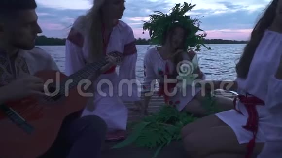 三个女孩和一个吉他手坐在码头上视频的预览图