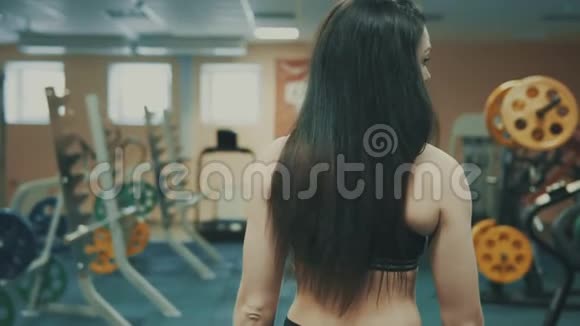 优雅的女士在运动俱乐部的健身器材间穿行视频的预览图
