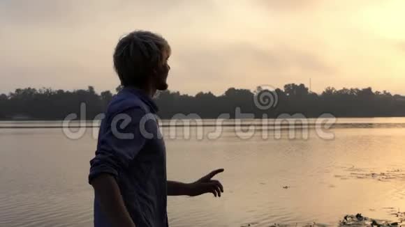 在斯隆莫的夕阳下欢乐的男人在令人印象深刻的河岸上跳舞视频的预览图