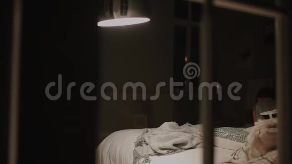 穿着睡衣的男孩在他家卧室的床上跳笑玩玩具视频的预览图