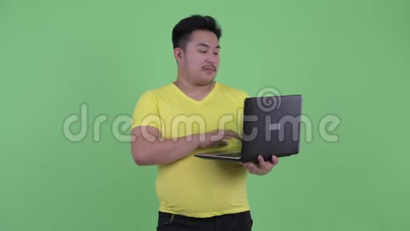 快乐年轻的超重亚洲男人使用笔记本电脑视频的预览图