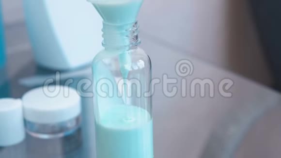 将蓝色洗发水倒入一小瓶大的漏斗中旅行的罐子瓶子特写视频的预览图