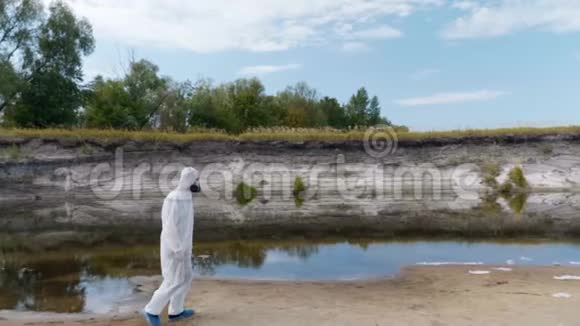 一个穿着防护服和呼吸器的人沿着干河散步估计污染的程度视频的预览图