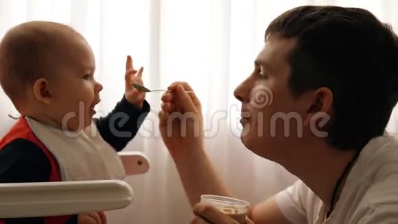 年轻快乐的父亲给儿子喂粥视频的预览图